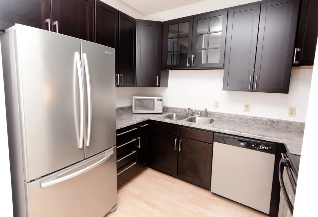 Modern kitchen with stainless steel appliances and cherry wood cabinets at Campus Oaks Apartments